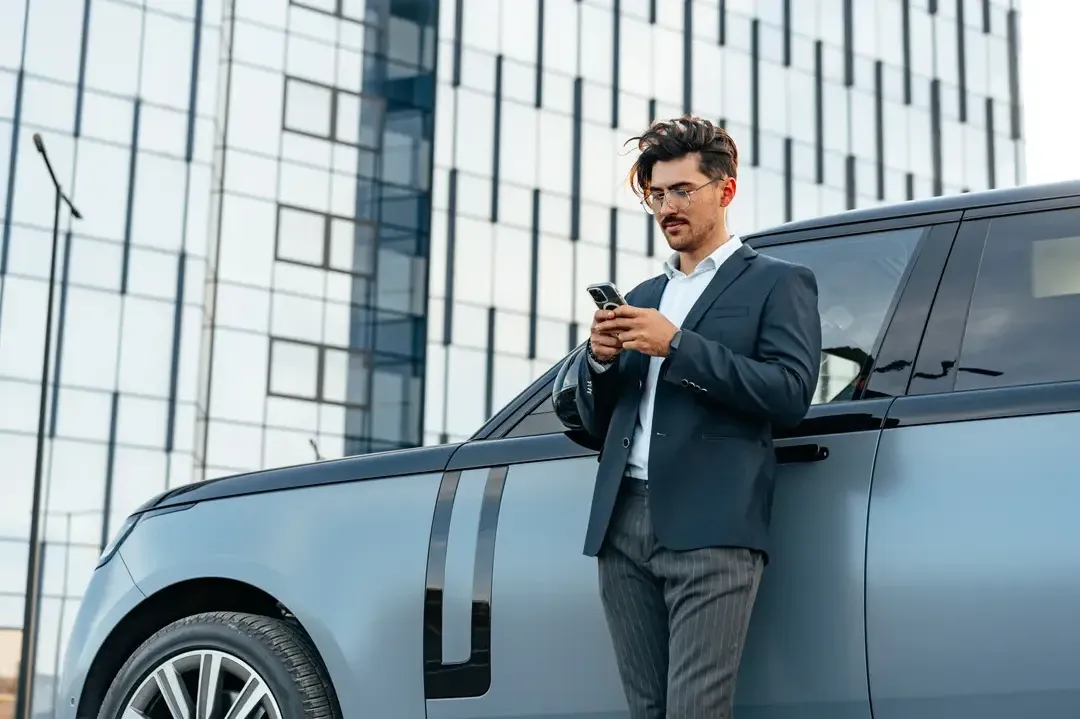 Businessman leaning on car